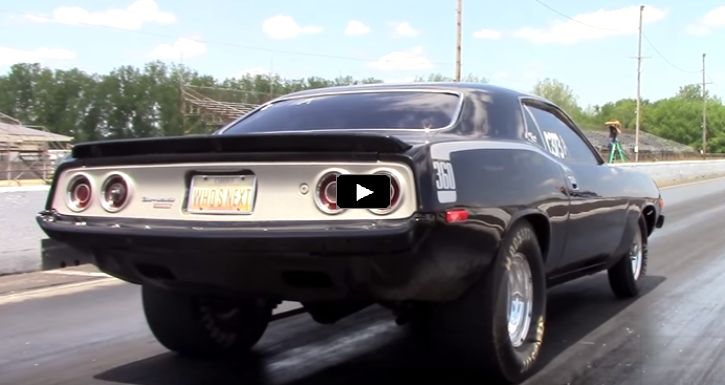 a black muscle car driving down the road