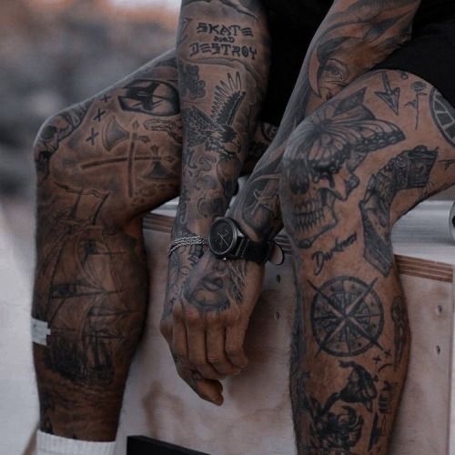 a man sitting on top of a skateboard covered in lots of tattooed arm tattoos