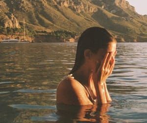 a woman sitting in the water with her hand to her face