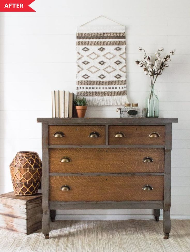 a wooden dresser with drawers and vases on top in a white room next to a wall