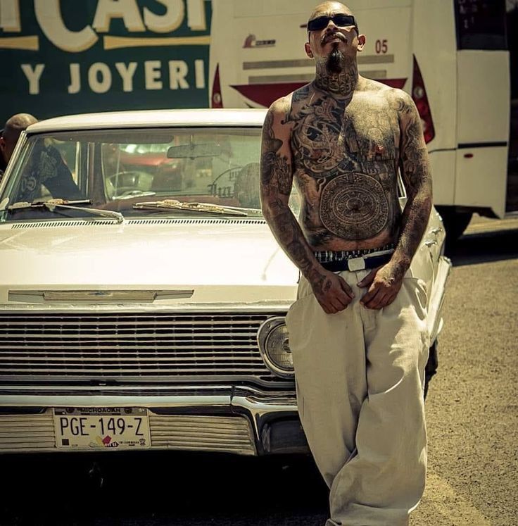 a tattooed man standing next to a white car