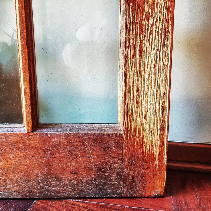 an old wooden window frame with peeling paint on the glass and wood grains in it