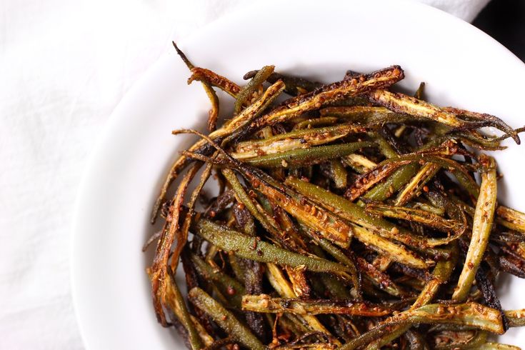 a white bowl filled with green beans on top of a table