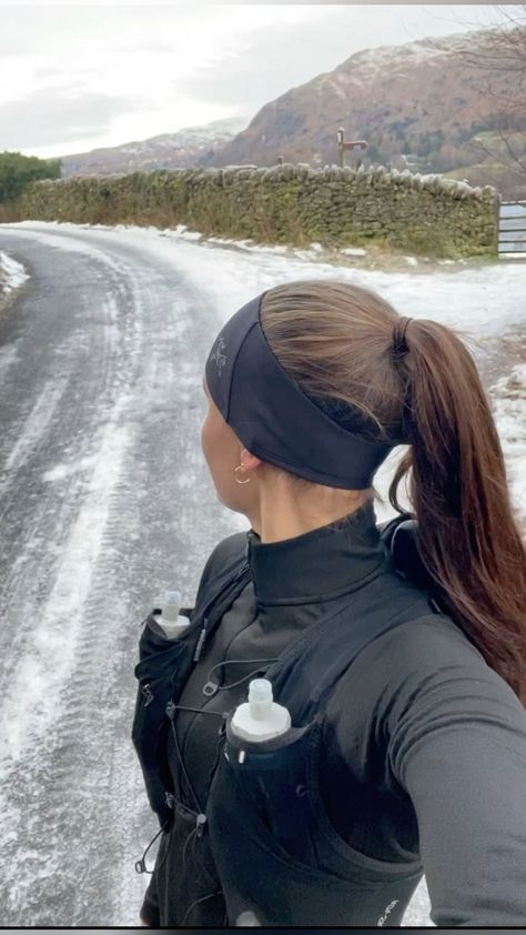 a woman standing on the side of a snow covered road with her back to the camera