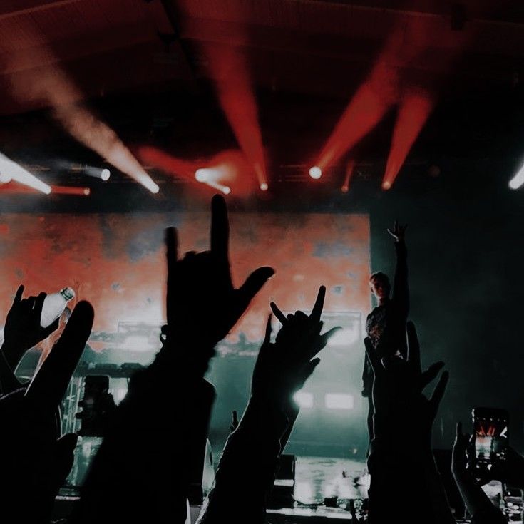 a group of people raising their hands up in the air at a music concert with lights on