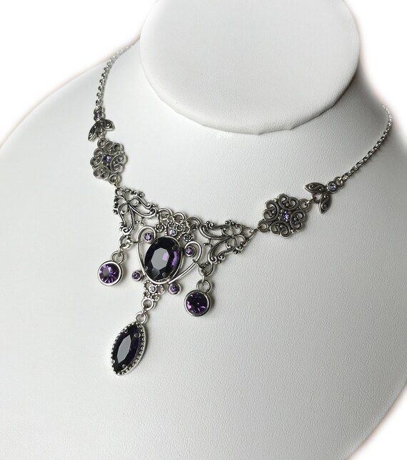 This lovely necklace is made with antiqued silver plated filigrees, adorned with dazzling DEEP VIOLET PURPLE glass rhinestones and jewels. Decorated portion measures 5" wide and 2 1/8" tall in the center. It is adjustable 15" to 18" in length and fastens with a lobster clasp.This is available in a variety of stone colors in our store, along with matching earrings and headpieces. If you don't see something with the stone color you'd like, feel free to send us a message. Victorian Jewelry Necklace, Victorian Necklace, Choker Pendant, Goth Jewelry, Purple Jewelry, Violet Purple, Bridesmaid Wedding, Amethyst Purple, Wedding Jewellery Necklace