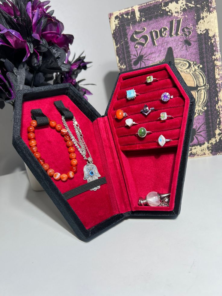 an open red velvet jewelry box next to purple flowers