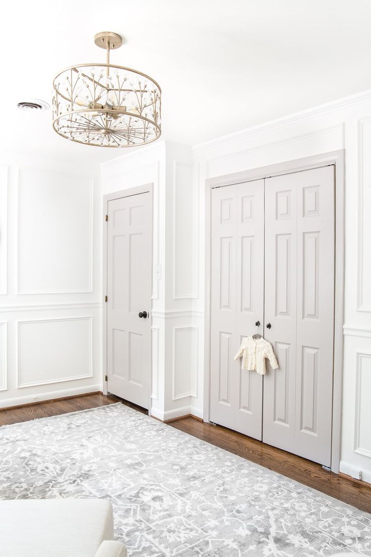 an empty room with two white doors and a chandelier hanging from the ceiling