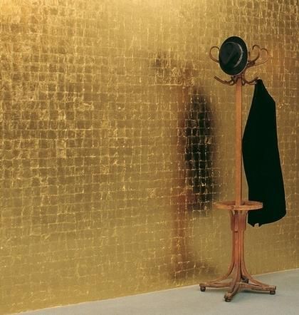 a coat rack with a hat and jacket on it in front of a gold wall