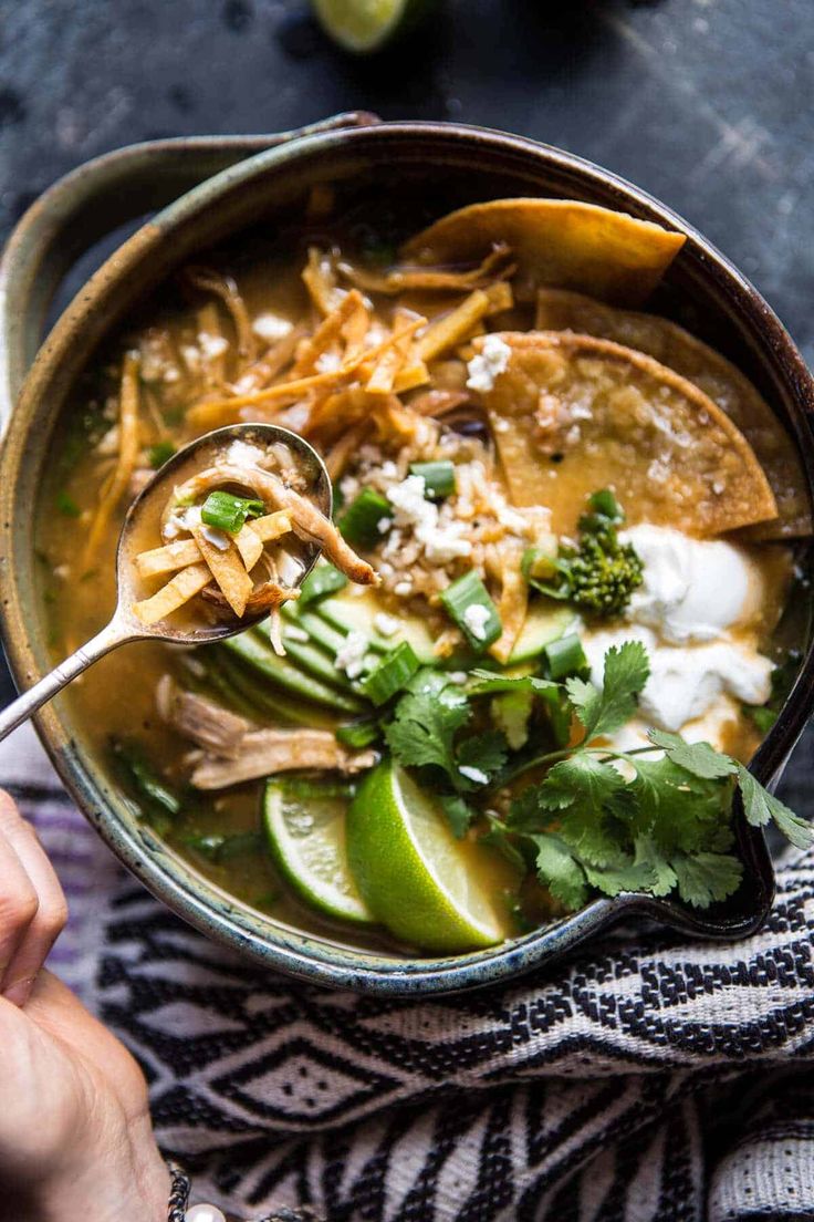 a bowl of chicken tortilla soup with cilantro, limes and sour cream