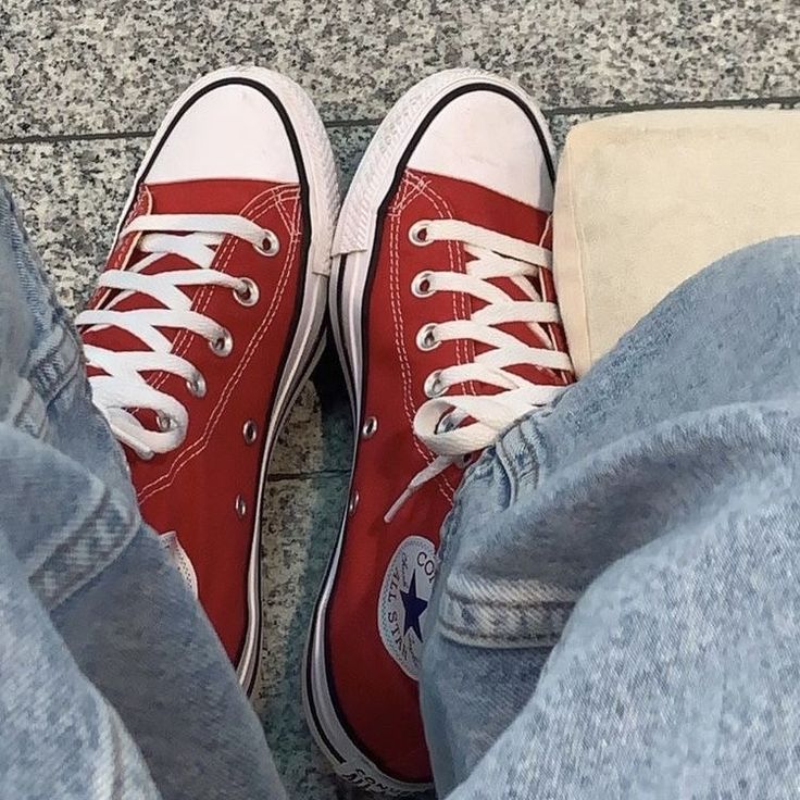 a person wearing red converse shoes sitting on the ground