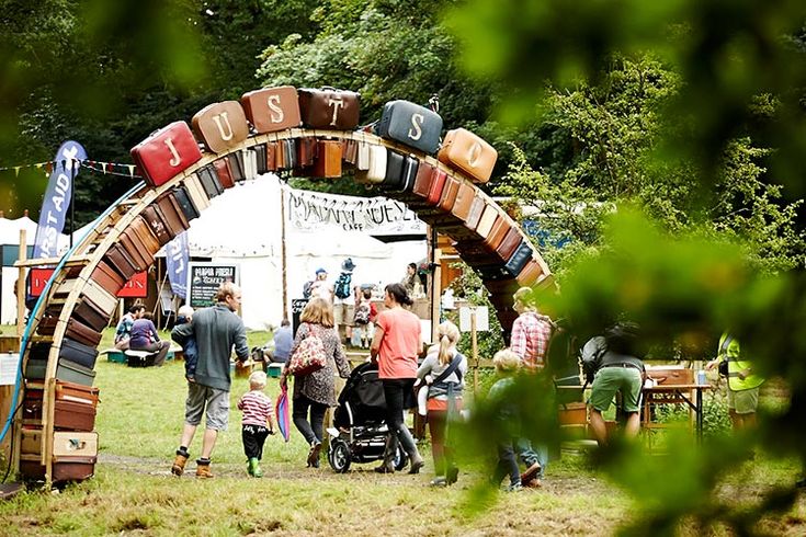 a group of people standing under an arch made out of suitcases at a festival