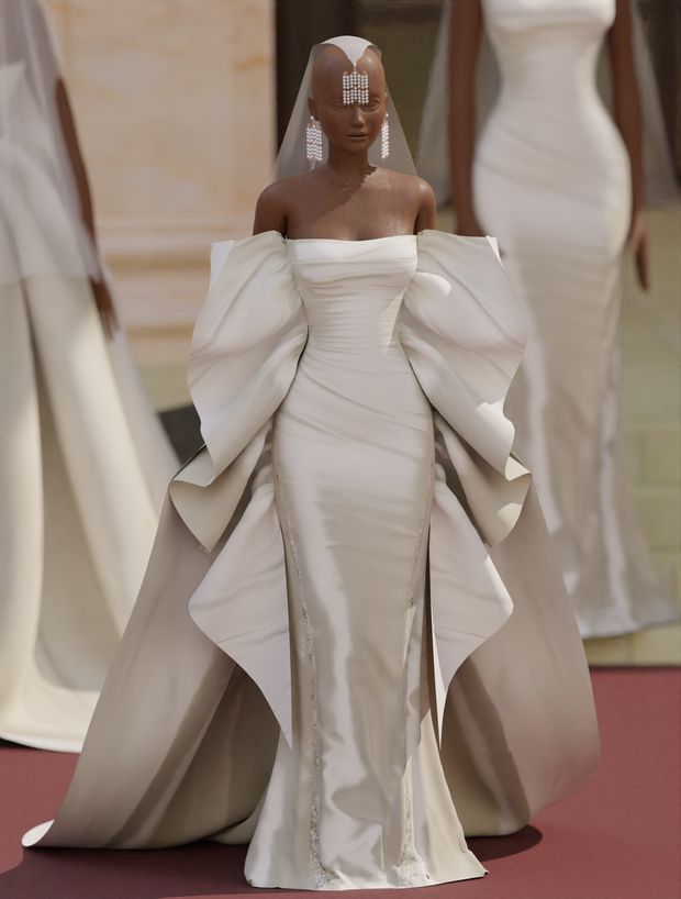 a woman in a white wedding gown and veil on the runway with other models behind her