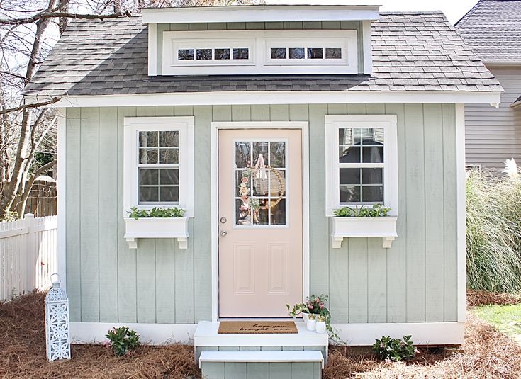 a small gray house with white trim and windows