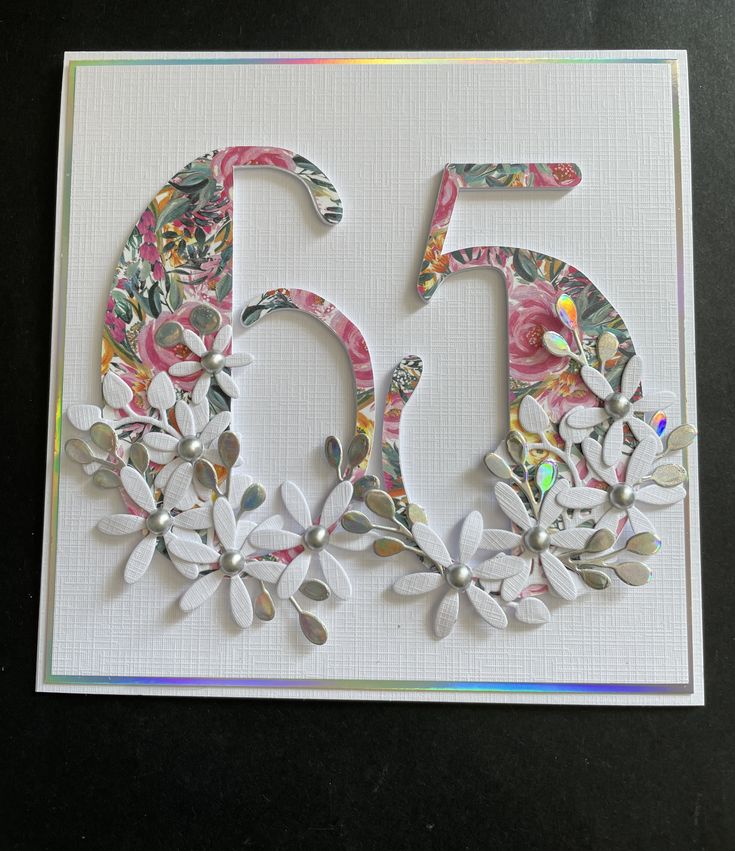 the number 50 is decorated with flowers and leaves on a white paper card that reads 50th