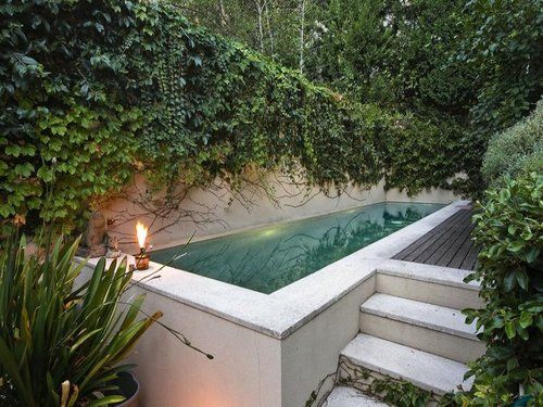 an outdoor pool surrounded by greenery and stairs