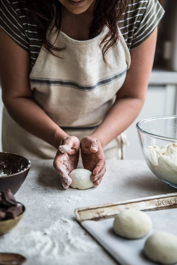 a woman is kneading dough into small balls on a table with utensils