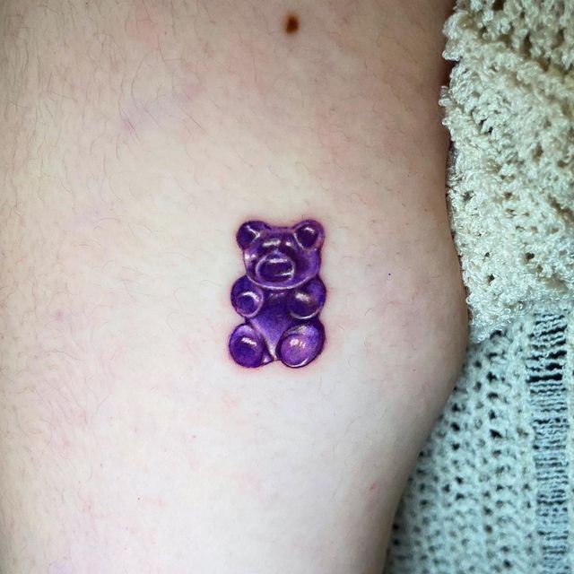 a small purple teddy bear tattoo on the right thigh