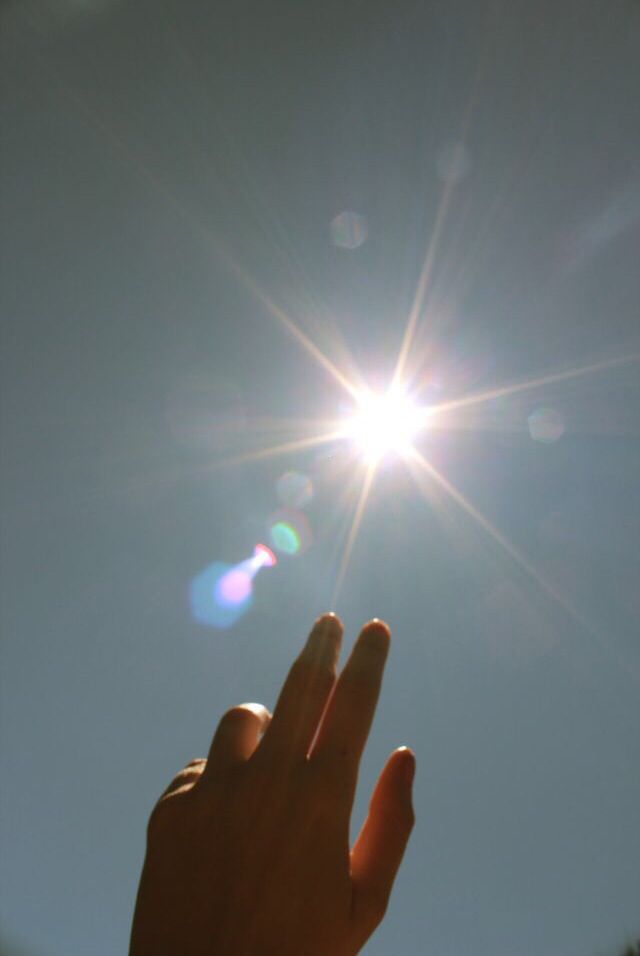 the sun shines brightly in the sky as someone holds their hand up to catch it