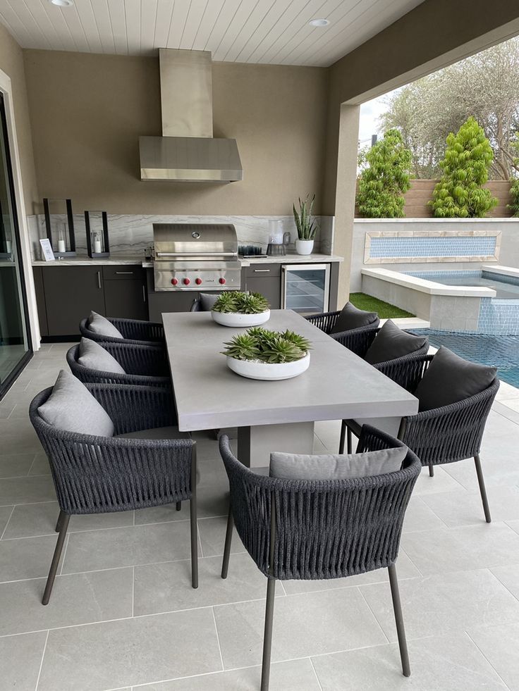 an outdoor dining area with table and chairs next to the swimming pool in the background