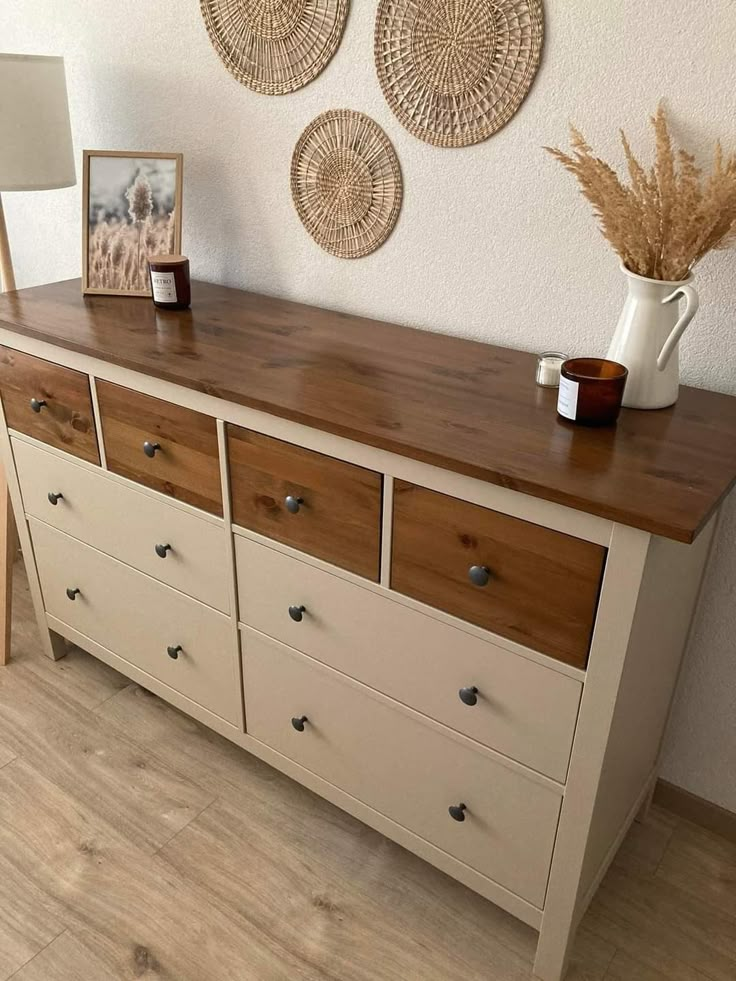 a dresser with drawers and baskets on the wall next to two pictures hanging above it