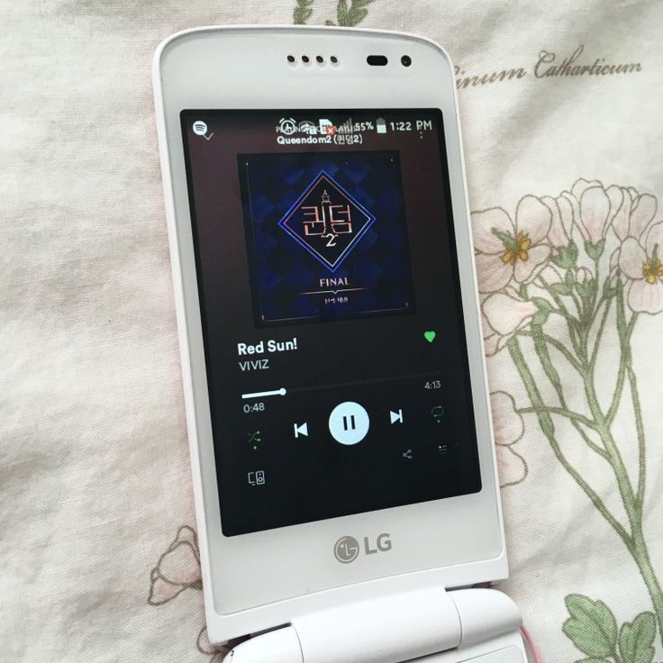 a white cell phone sitting on top of a bed next to a flowered blanket