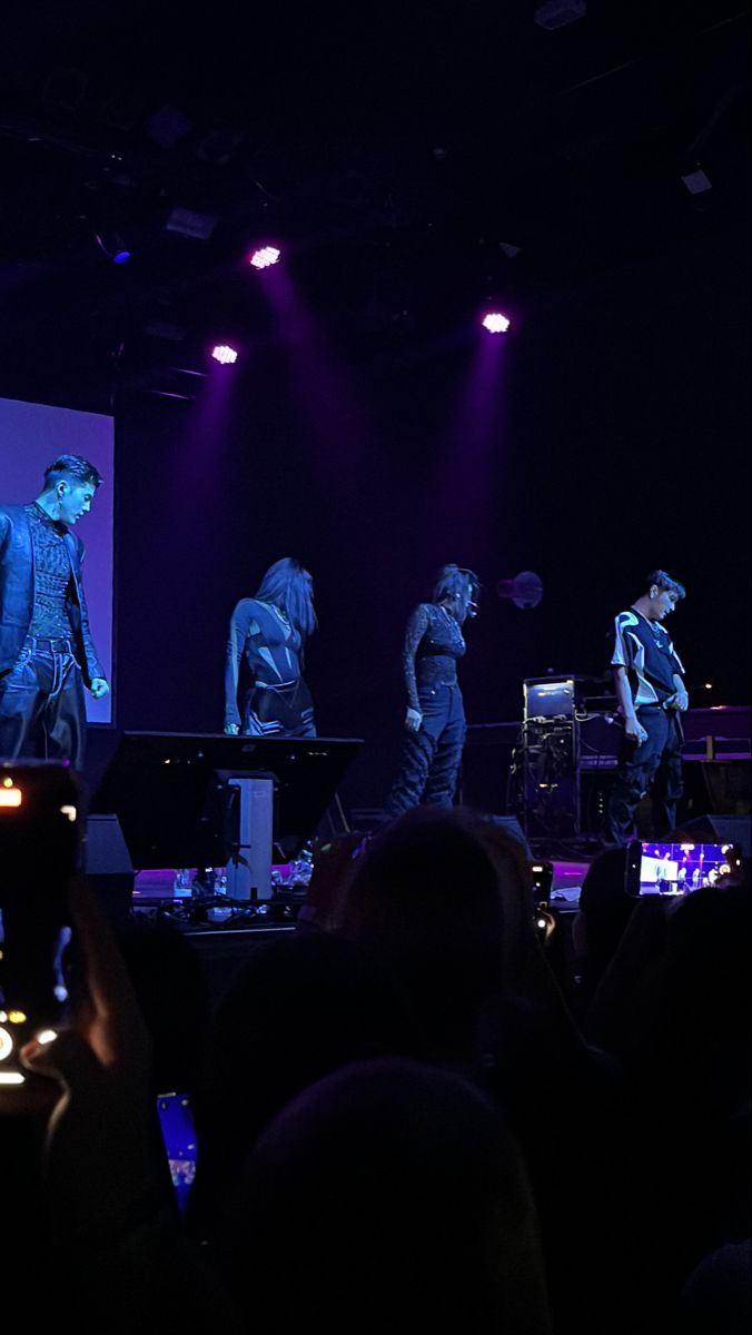 a group of people standing on top of a stage in front of a crowd at night