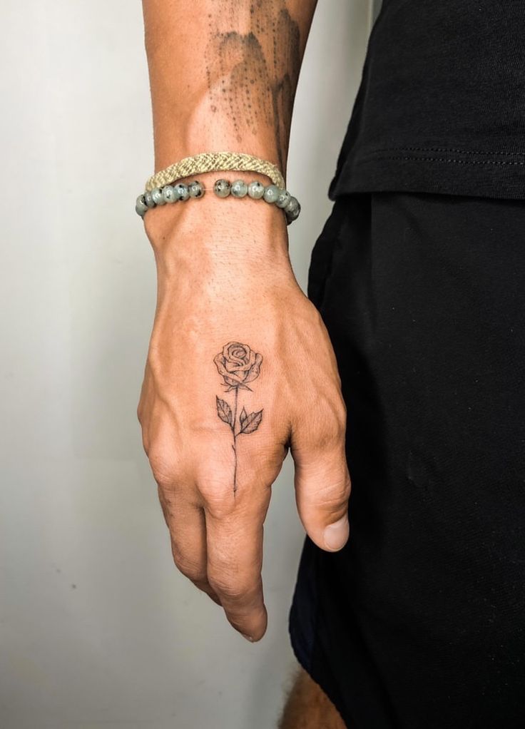 a man with a rose tattoo on his hand and wrist is holding onto a bracelet