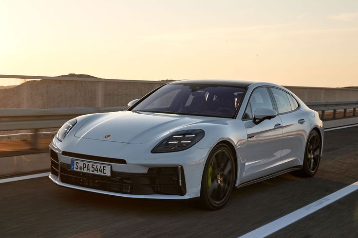 a white porsche panameia is driving down the road