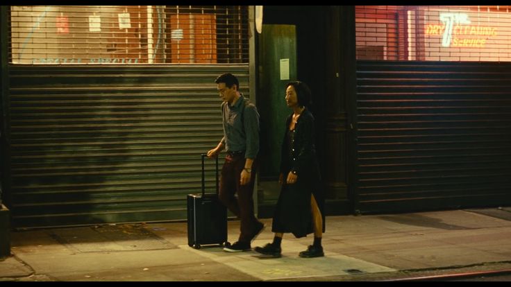 a man and woman walking down the street with luggage