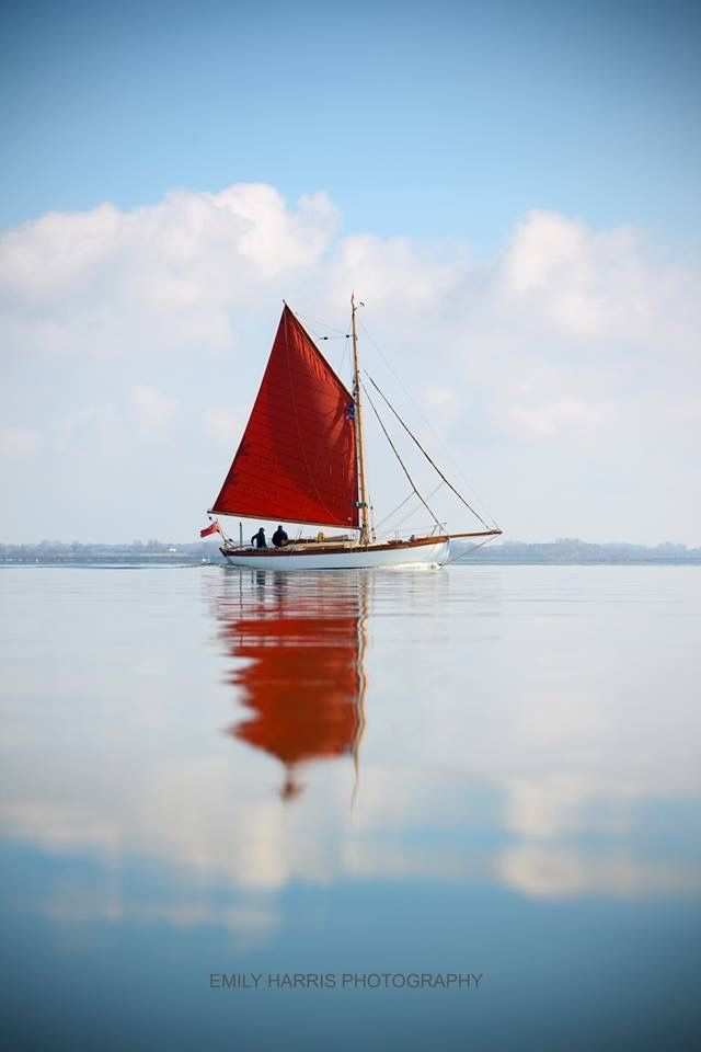 a red sailboat floating on top of a large body of water