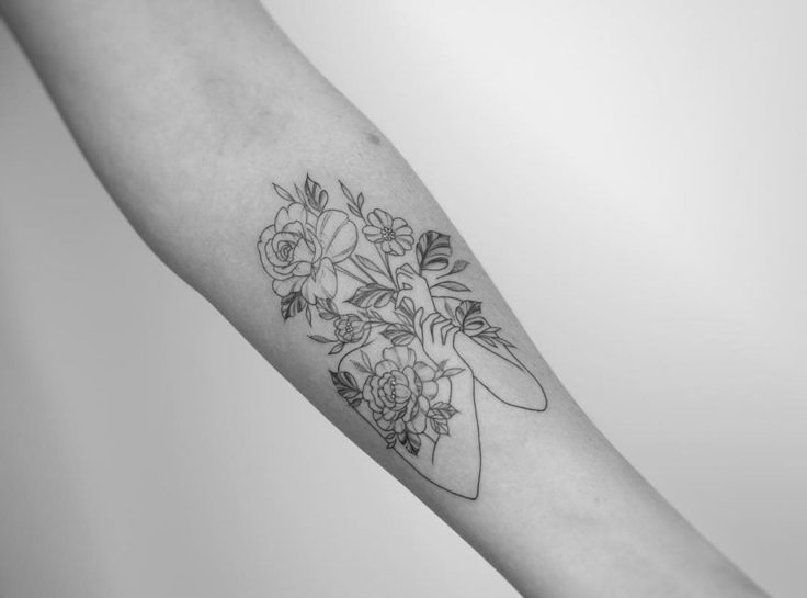 a black and white photo of a woman's arm with flowers on it