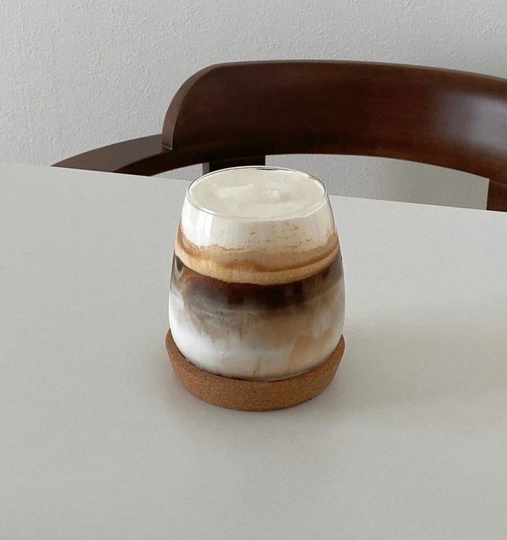 a white and brown cup sitting on top of a table next to a wooden chair