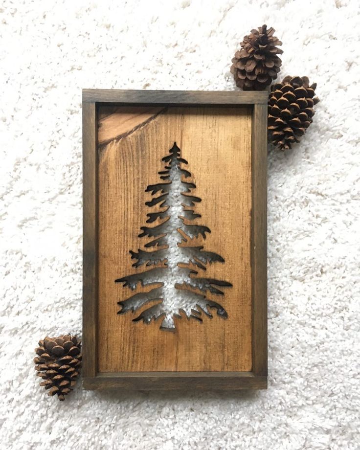 some pine cones are sitting on the floor next to a wooden frame with a tree in it