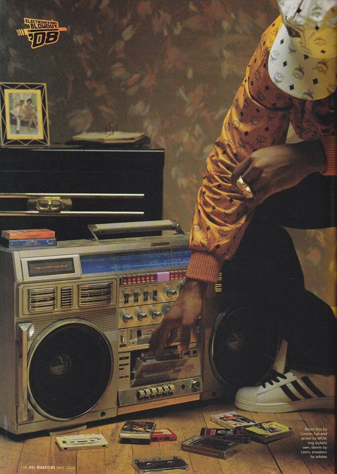 a man sitting on the floor next to an old radio and boombox with his feet propped up against it