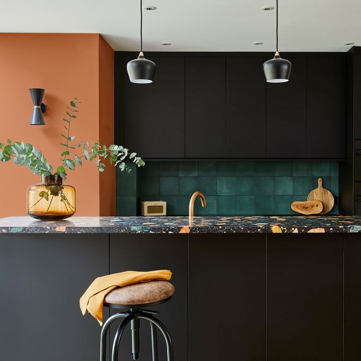 an orange and black kitchen with two stools in front of the island countertop