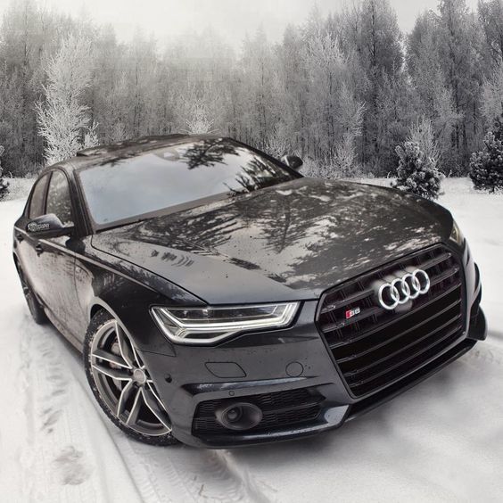 a black car parked in the snow near trees