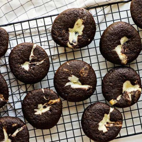 chocolate cookies with white icing on a cooling rack