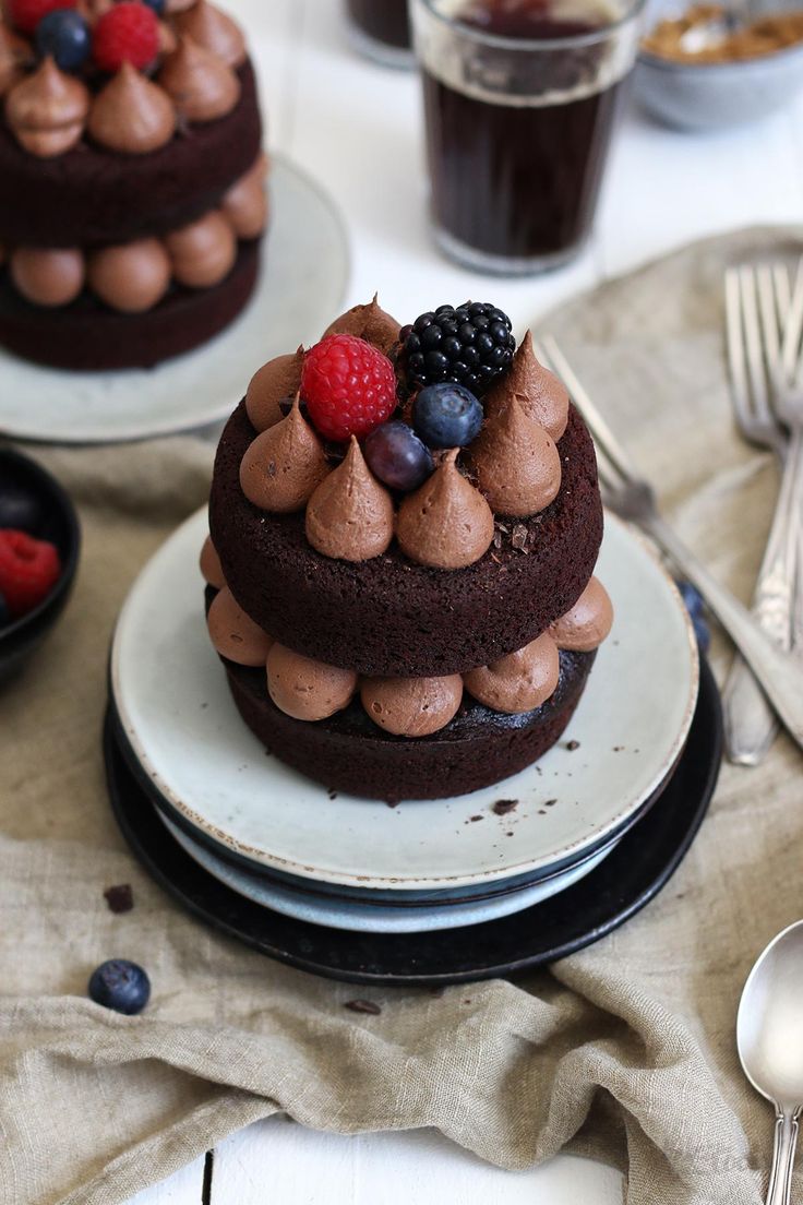 two chocolate cakes on plates with berries, raspberries and blueberries