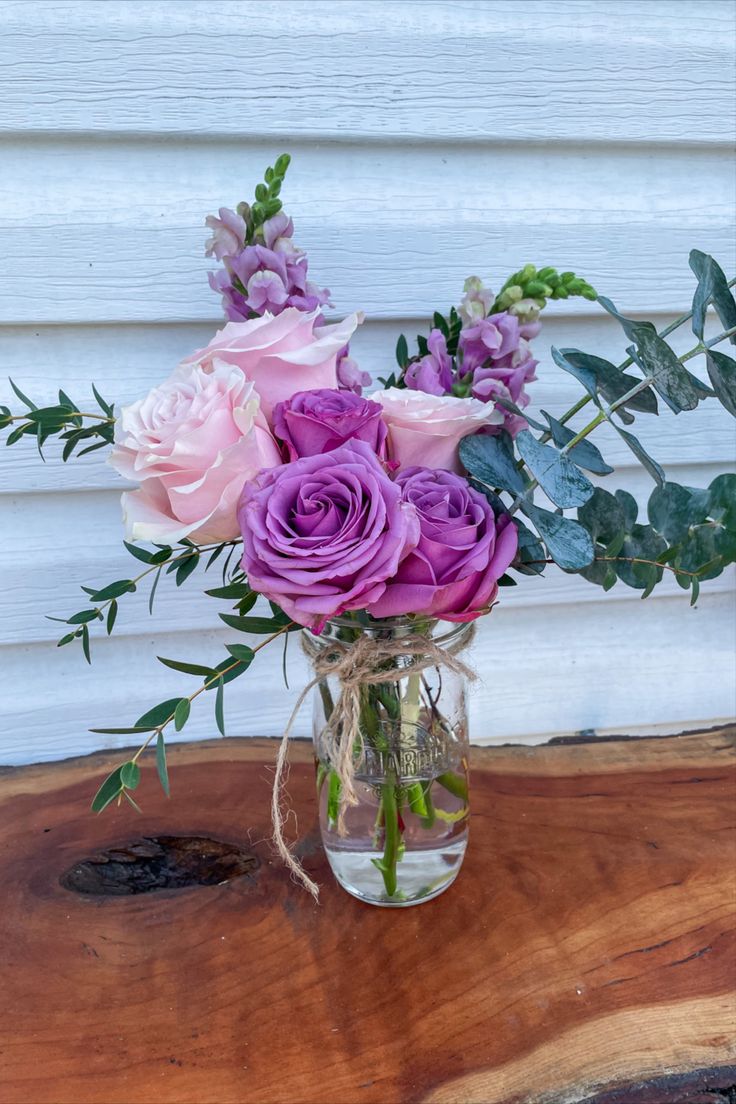 a vase filled with purple flowers on top of a wooden table