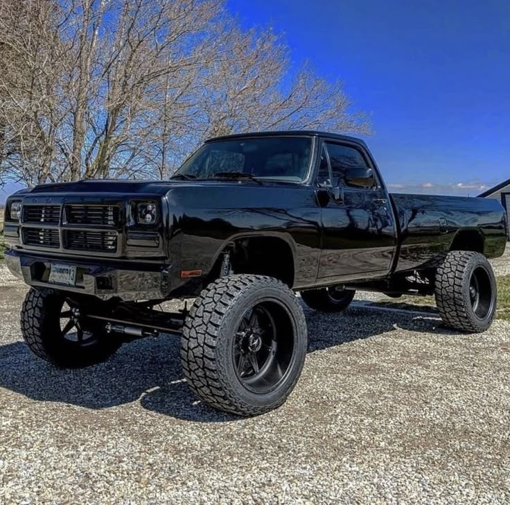 a black truck parked on top of a gravel field