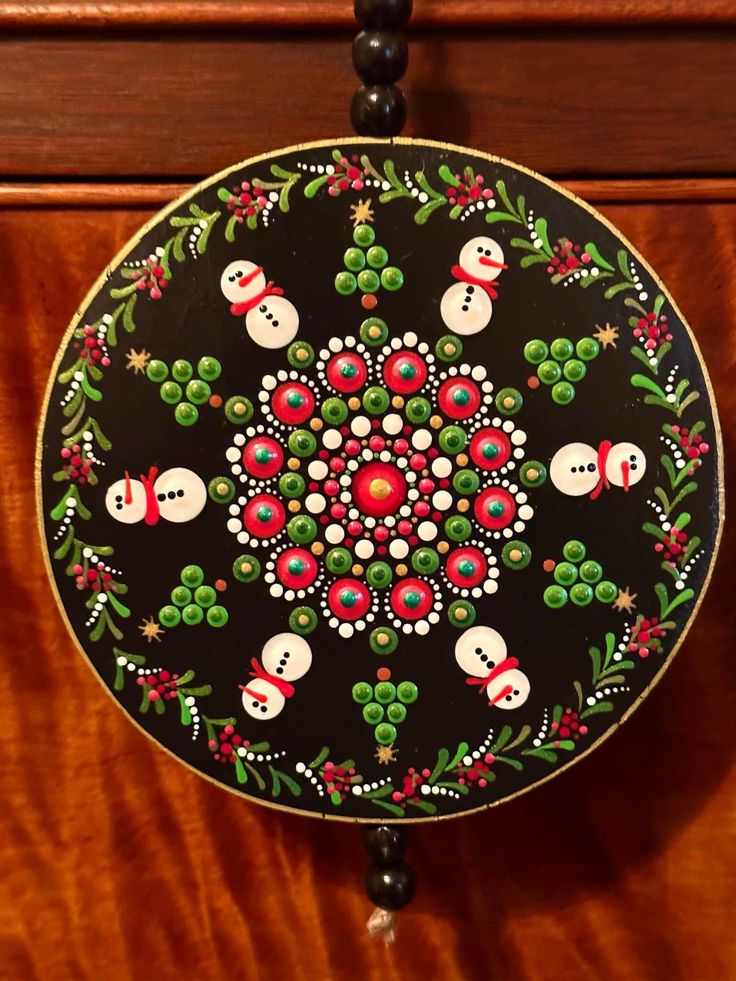 a black and red christmas ornament hanging from a wooden cabinet with holly wreaths on it