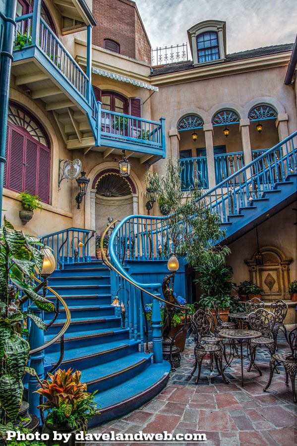 a blue staircase leading up to a building with tables and chairs in front of it