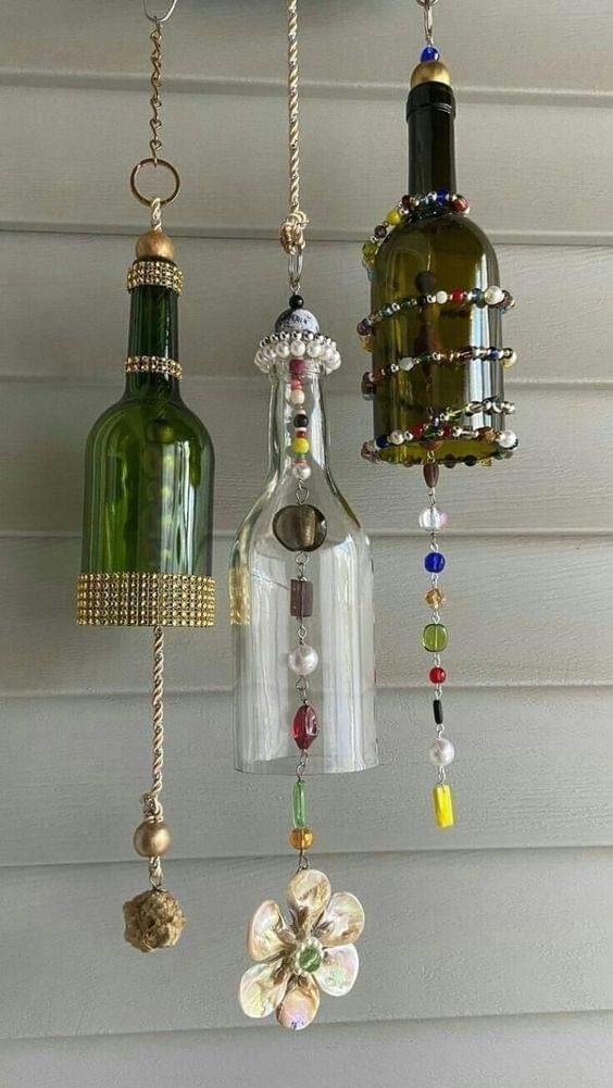 three wine bottles hanging from the side of a house with beads and chains attached to them