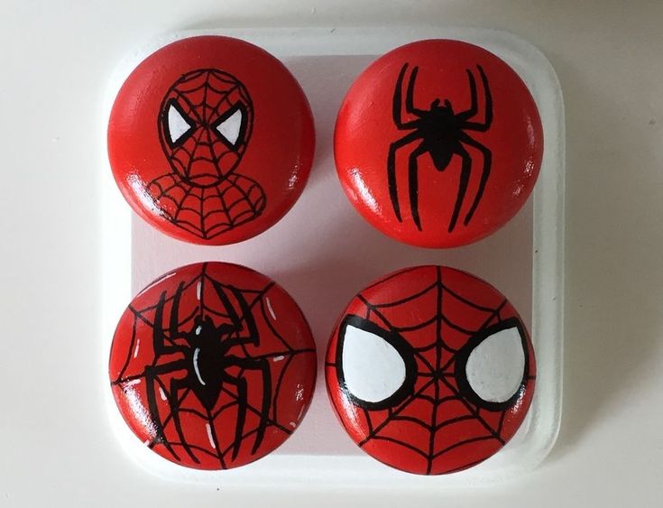 four spiderman buttons on a white surface