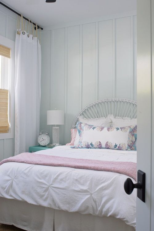 a white bed sitting next to a window in a bedroom under a light fixture on top of a hard wood floor