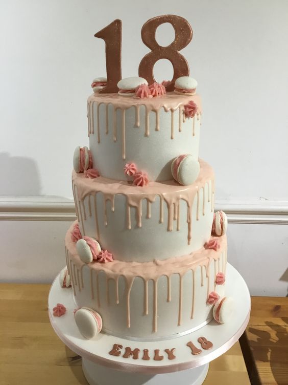 a three tiered birthday cake with pink icing and decorations on the bottom layer