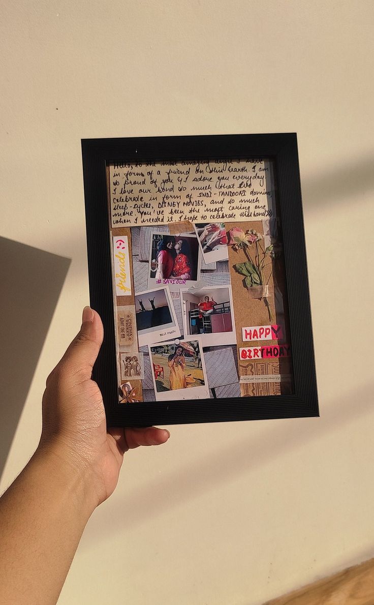 a person holding up a framed photo with pictures on it