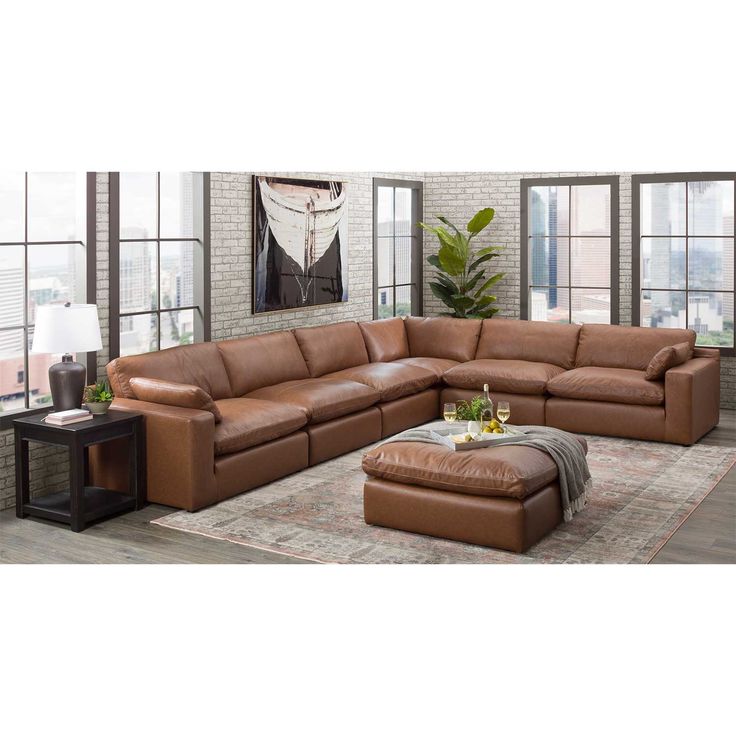 a living room with a large sectional couch and ottoman