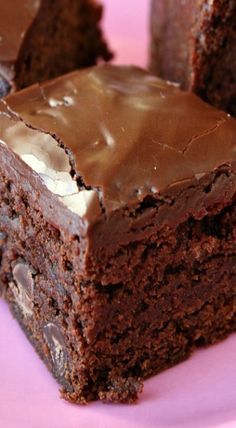 a close up of a piece of cake on a pink plate with chocolate frosting